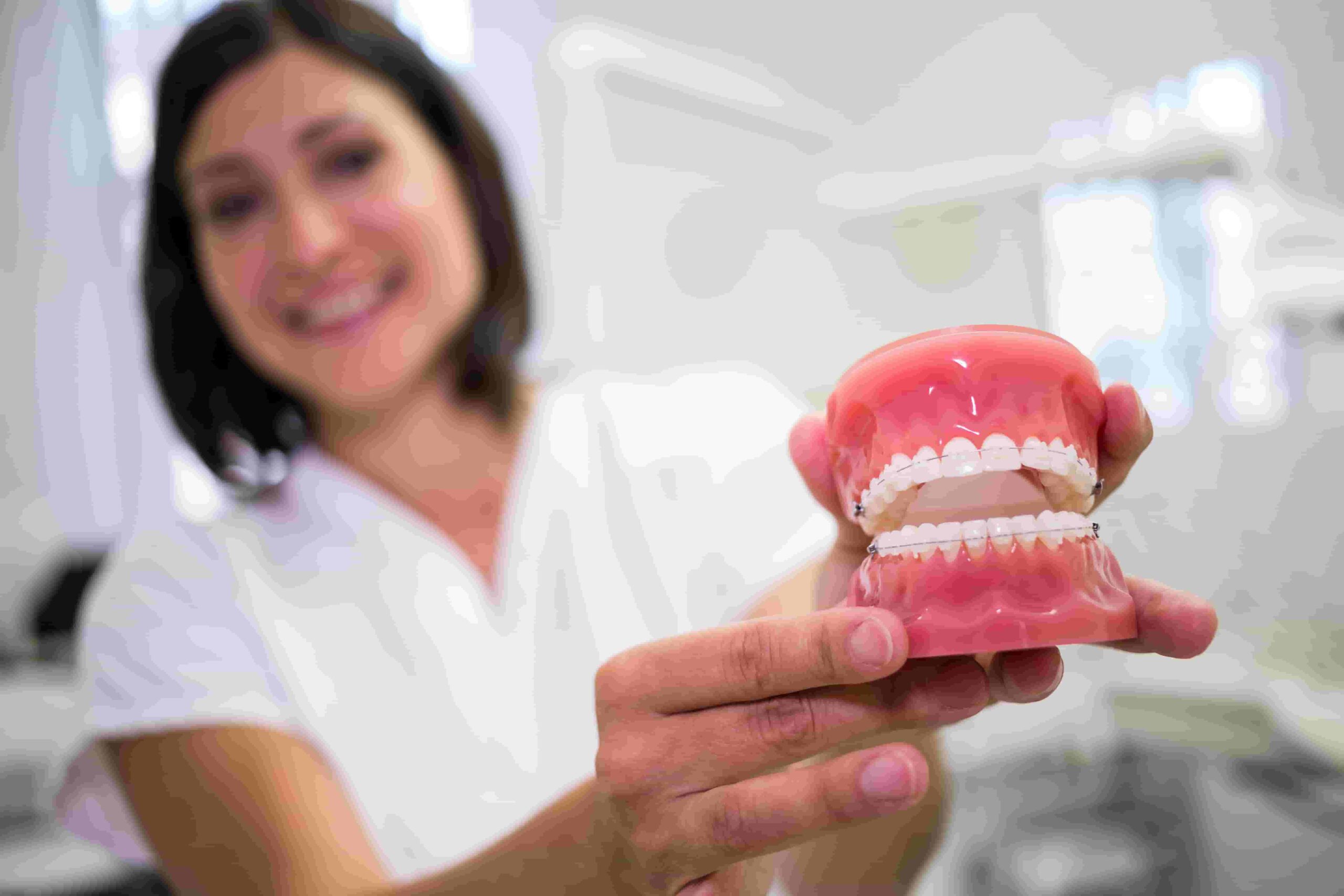 female dentist holding set of dentures